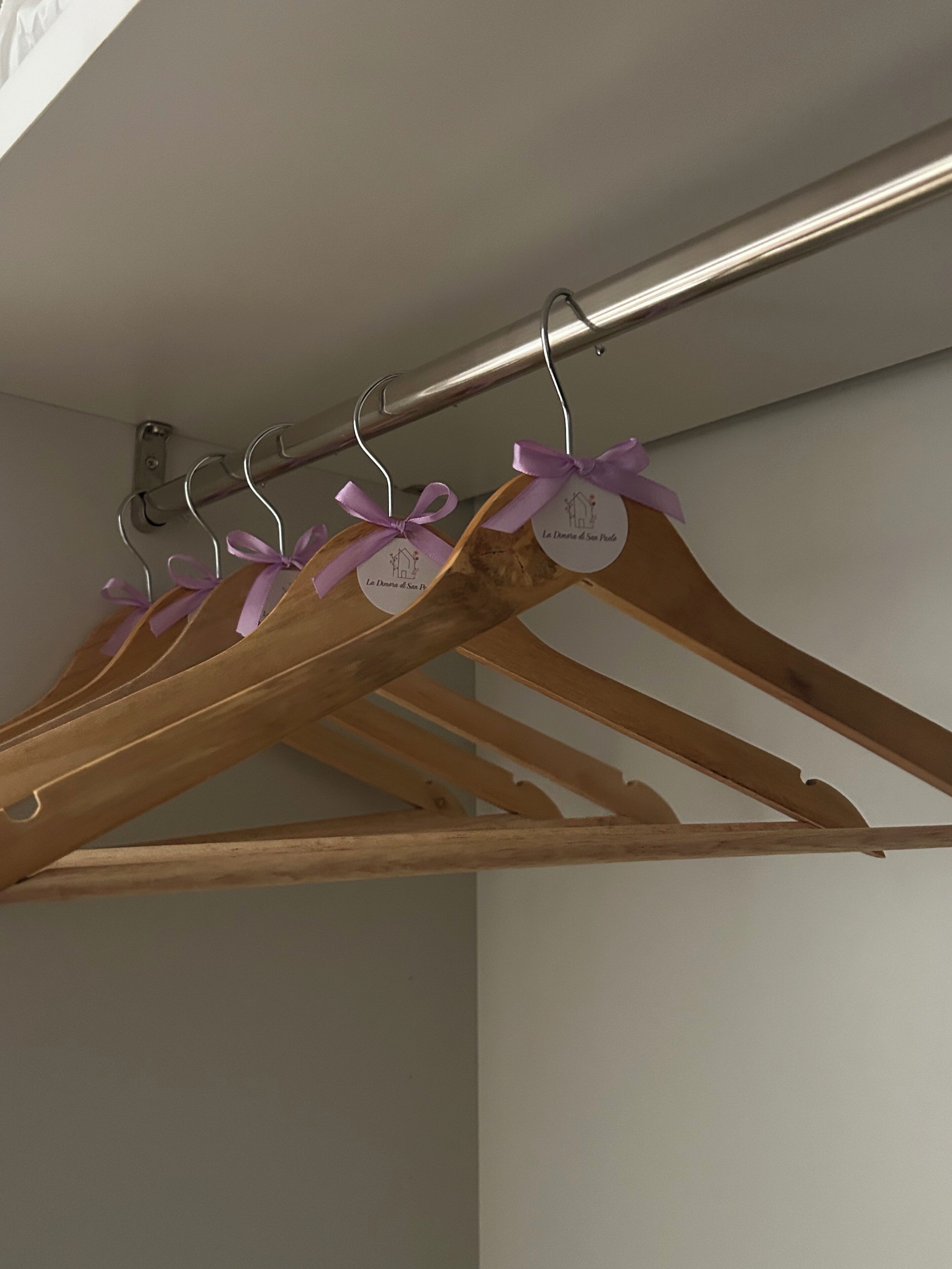 Ein Holzkleiderständer mit Kleiderbügeln, einige mit violetten Bändern.
