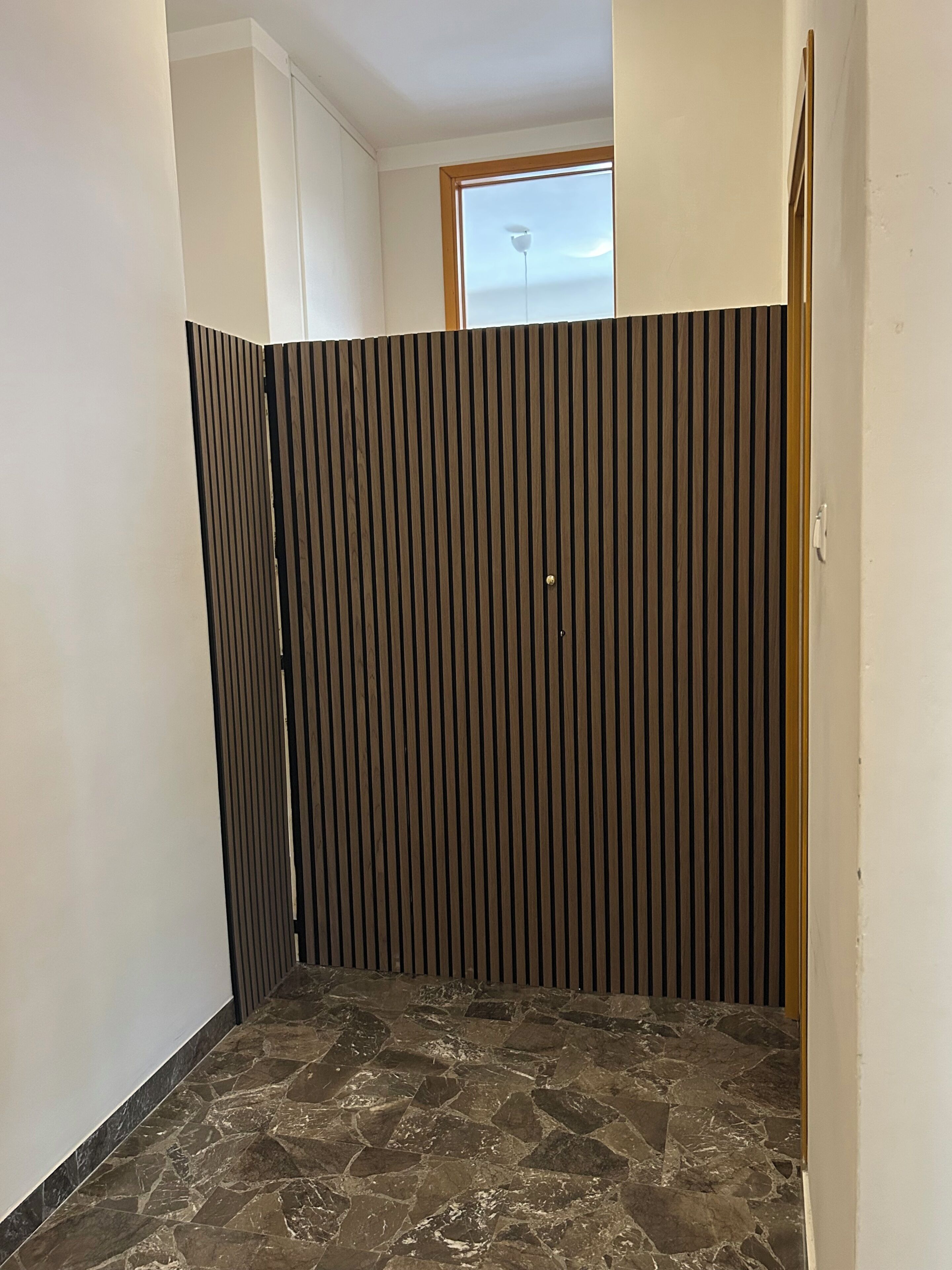A room with a stone floor, a wooden partition, and a window with a view.