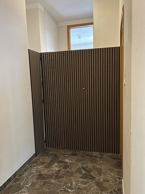 A room with a stone floor, a wooden partition, and a window with a view.
