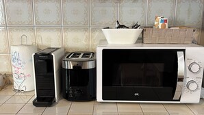 Una cocina con tostadora, cafetera y microondas en la encimera.