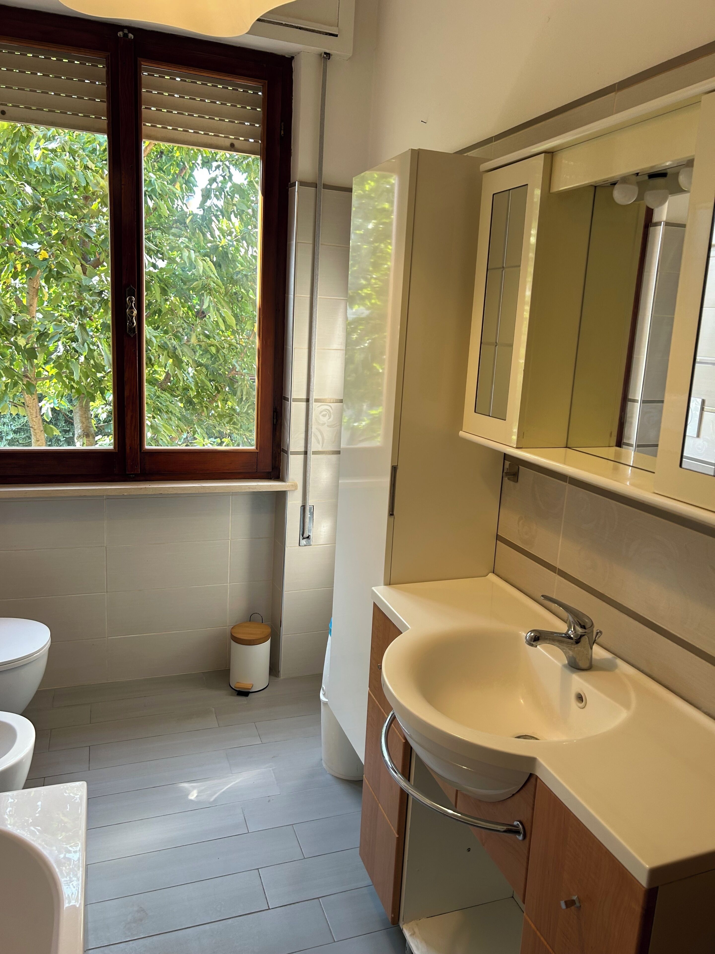 A bathroom with a toilet, sink, and window with blinds.