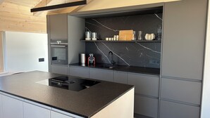 A modern kitchen with a black countertop, built-in oven, and a marble backsplash. - Mountain Ranges Around Lake Chiemsee (Übersee)