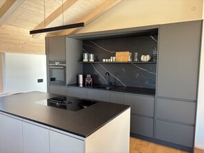 Eine moderne Küche mit schwarzem Arbeitsplatz, integriertem Backofen und einer Marmorspritzschutzwand.