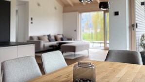 A modern kitchen with wooden beams, a dining table with chairs, and pendant lights. - Mountain Ranges Around Lake Chiemsee (Übersee)