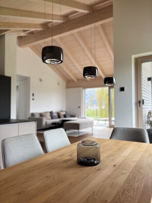 Eine moderne Küche mit Holzbalken, einem Esstisch mit Stühlen und Pendelleuchten.