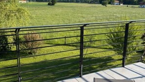 A terrace with a metal railing, a grassy field, and mountains in the background. - Mountain Ranges Around Lake Chiemsee (Übersee)