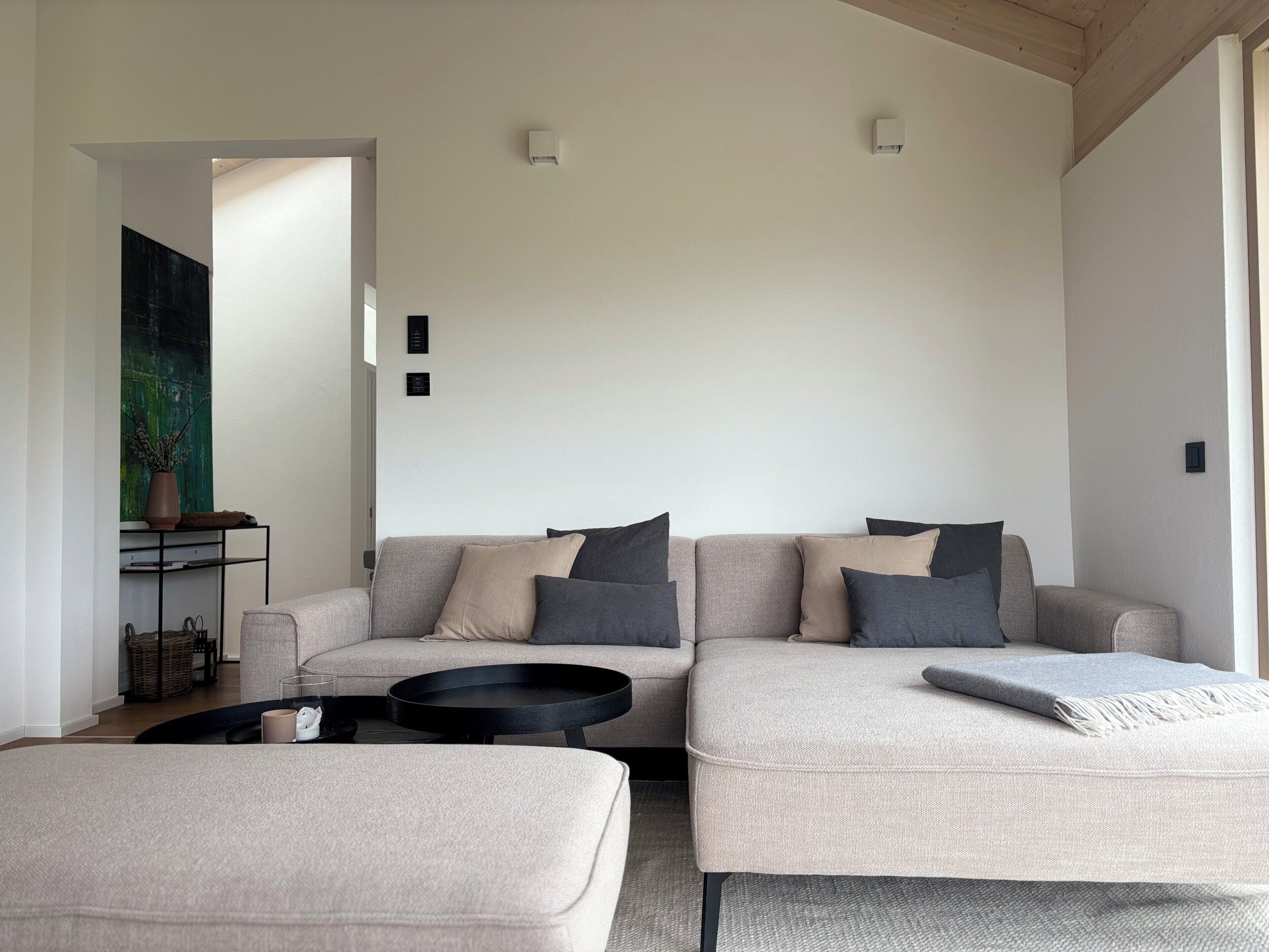 Un salon moderne avec deux canapés, une table basse et une table d’appoint sur laquelle est posé un vase.