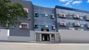 Un edificio moderno con varios balcones, fachada plana y cielo despejado.