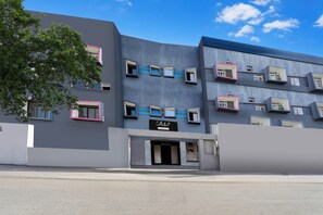 Un edificio moderno con varios balcones, fachada plana y cielo despejado.