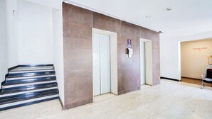 Vestíbulo de hotel con piso de mármol, una escalera y dos puertas con un cartel que dice 'No se permiten visitantes'.