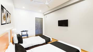 A hotel room with two beds, a chair, a door, and a television on the wall.
