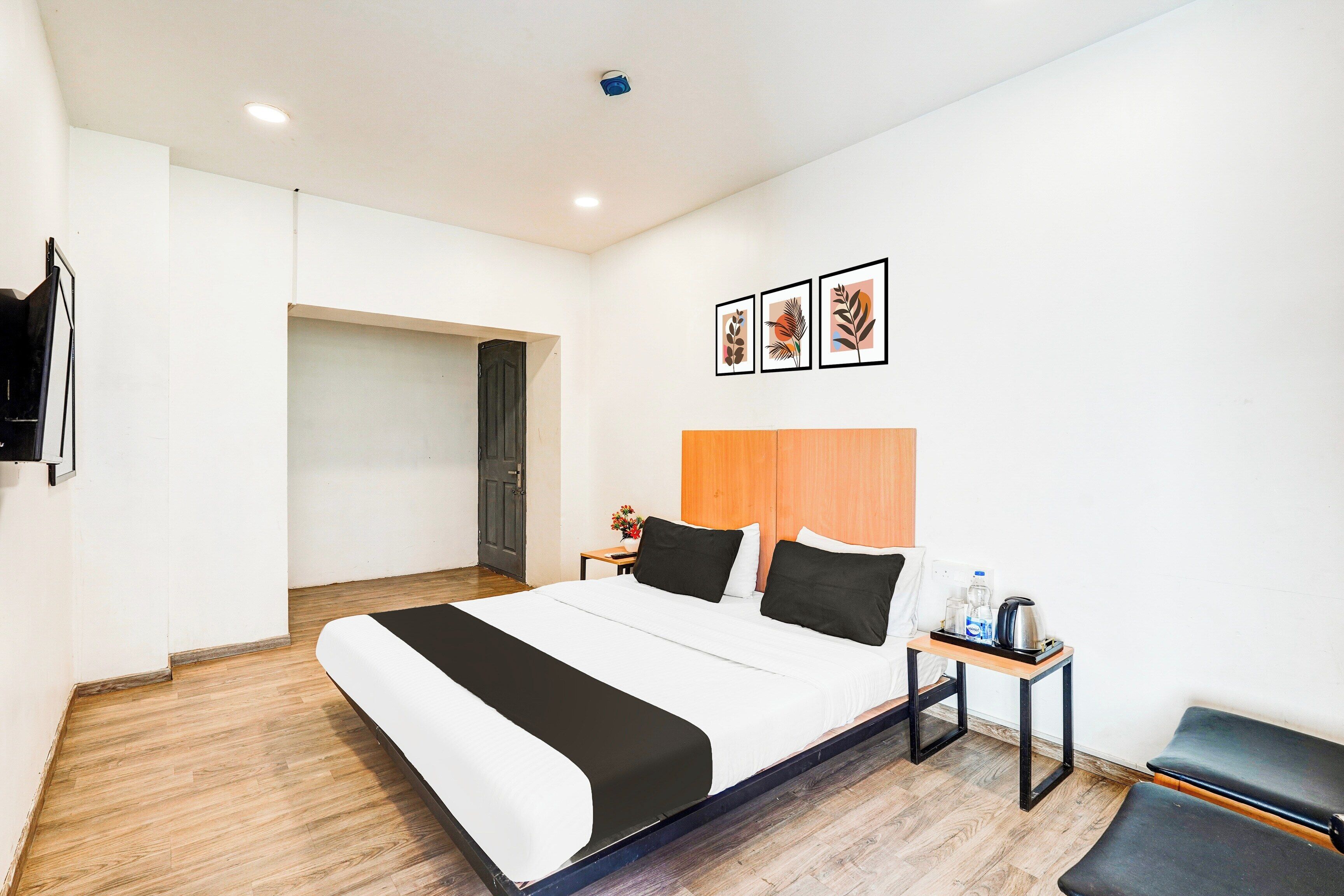 A hotel room with a bed, bedside table, and a small seating area.
