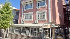 Ein pinkfarbenes Gebäude mit Balkon, großen Fenstern und einem geschlossenem Eingang.