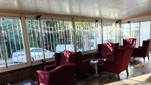 Ein Zimmer mit Holzböden, roten Polstersesseln und großen Fenstern mit Metallgitter.