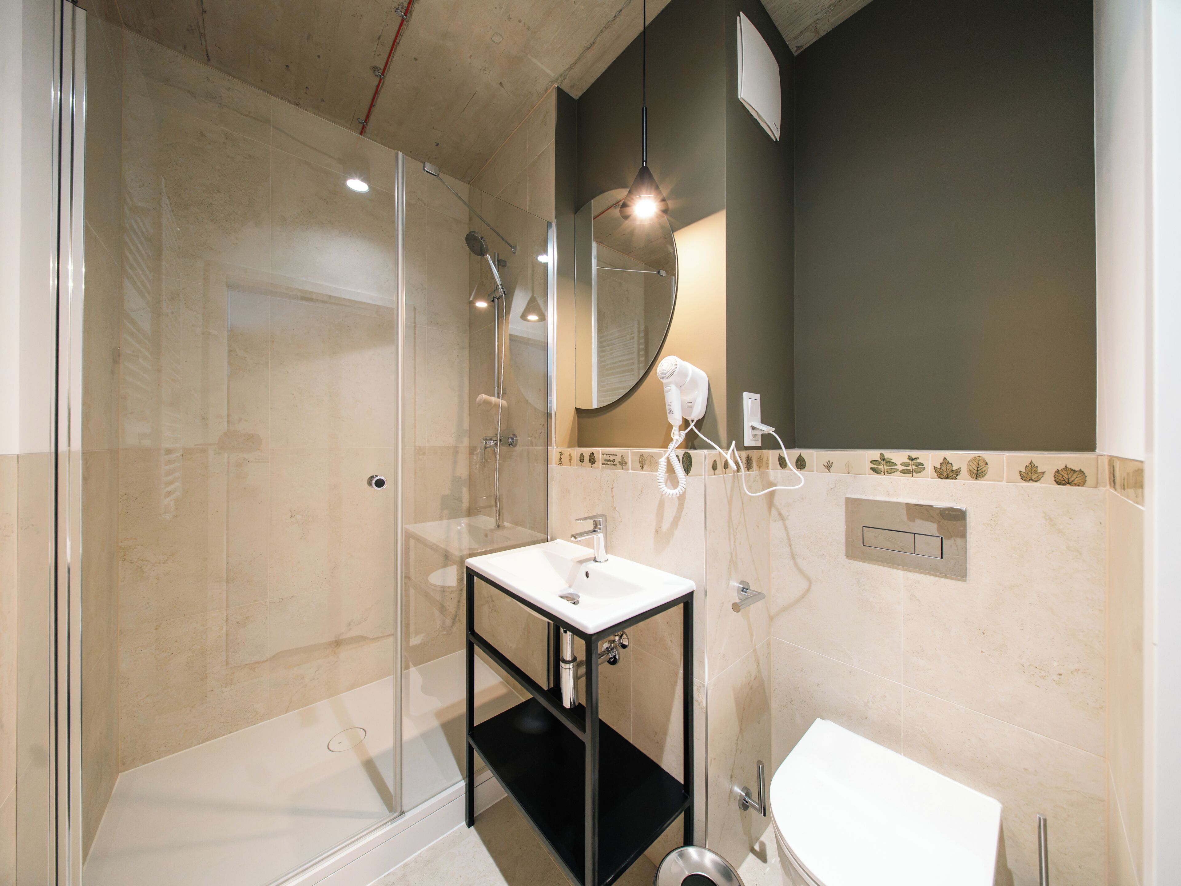 Un baño moderno con ducha de vidrio, lavamanos blanco y inodoro.