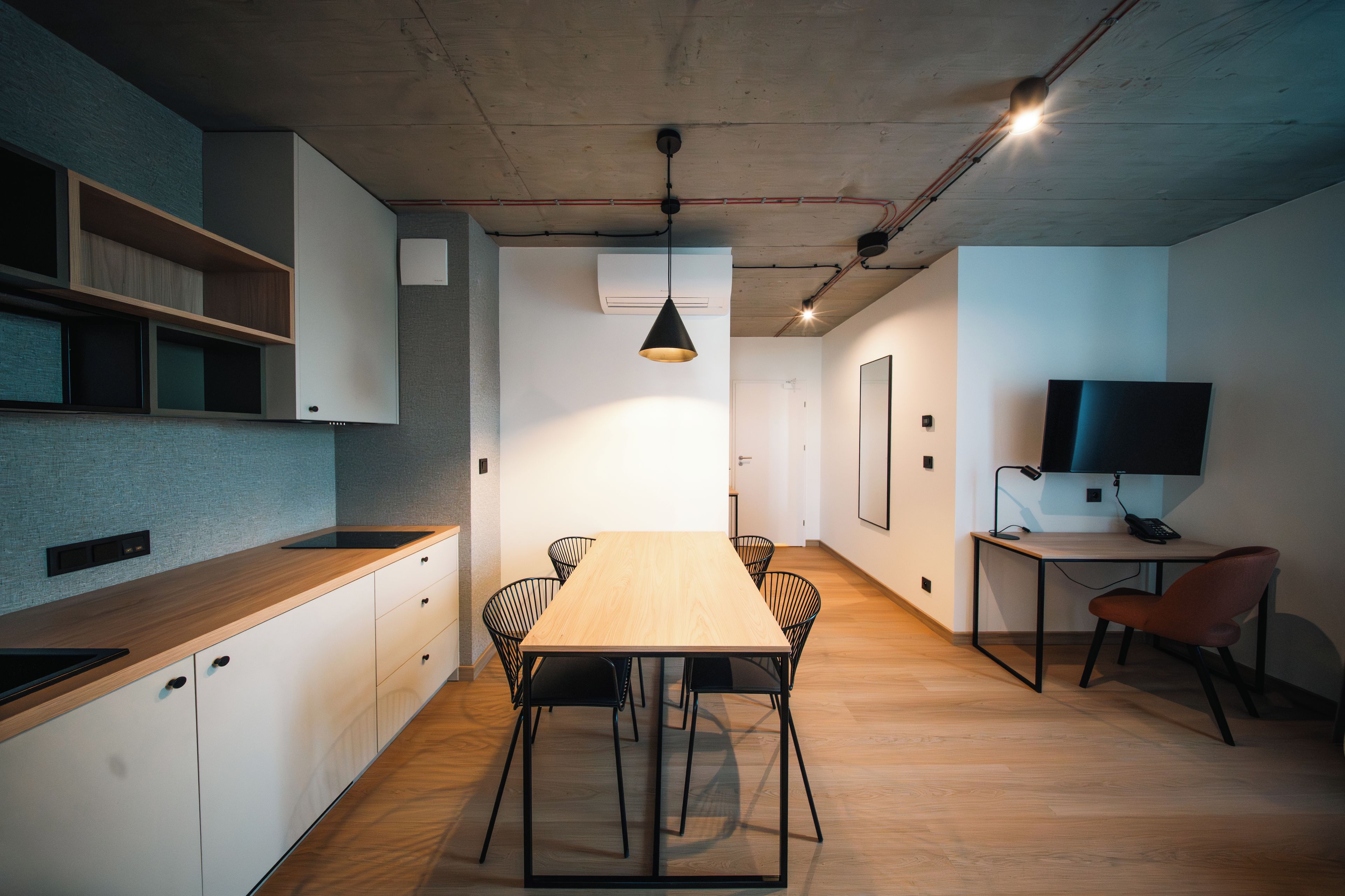 Una cocina moderna con encimera de madera, una mesa de comedor con sillas y un televisor sobre un escritorio.