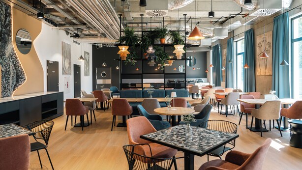 Un intérieur moderne avec des coins salon, des tables et des luminaires suspendus.