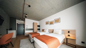 Une chambre d’hôtel moderne équipée de deux lits, d’un bureau, d’une chaise et d’œuvres d’art accrochées au mur.