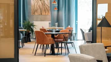 Interior de un restaurante con comedor, sillas, una mesa y un letrero sobre la entrada.