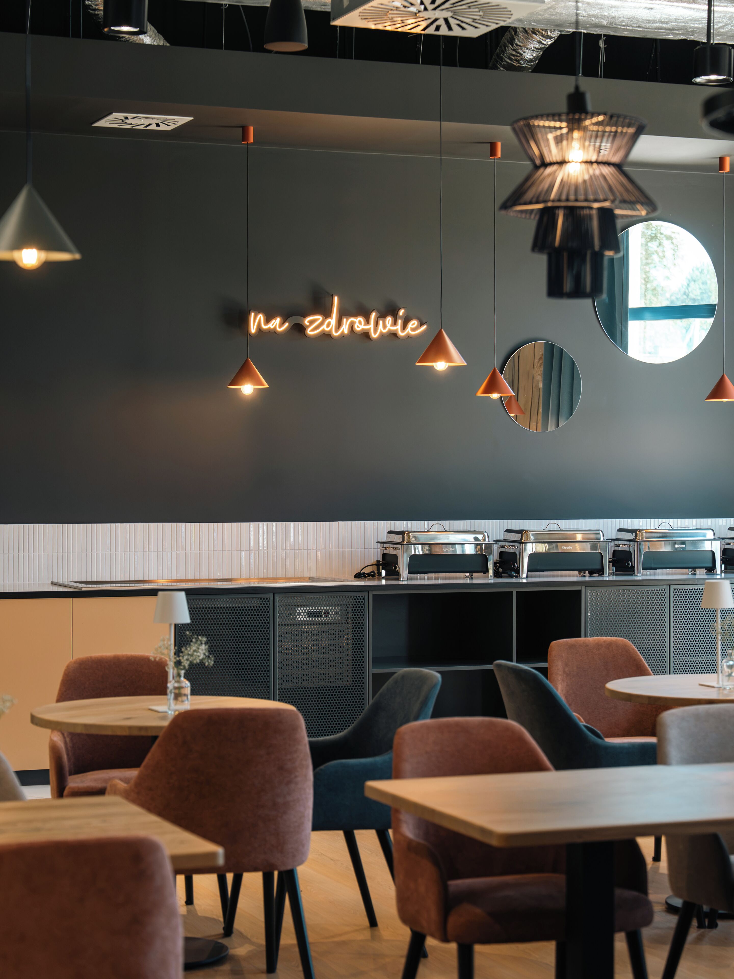 Een modern interieur met hanglampen, een neonbord en een kitchenette.