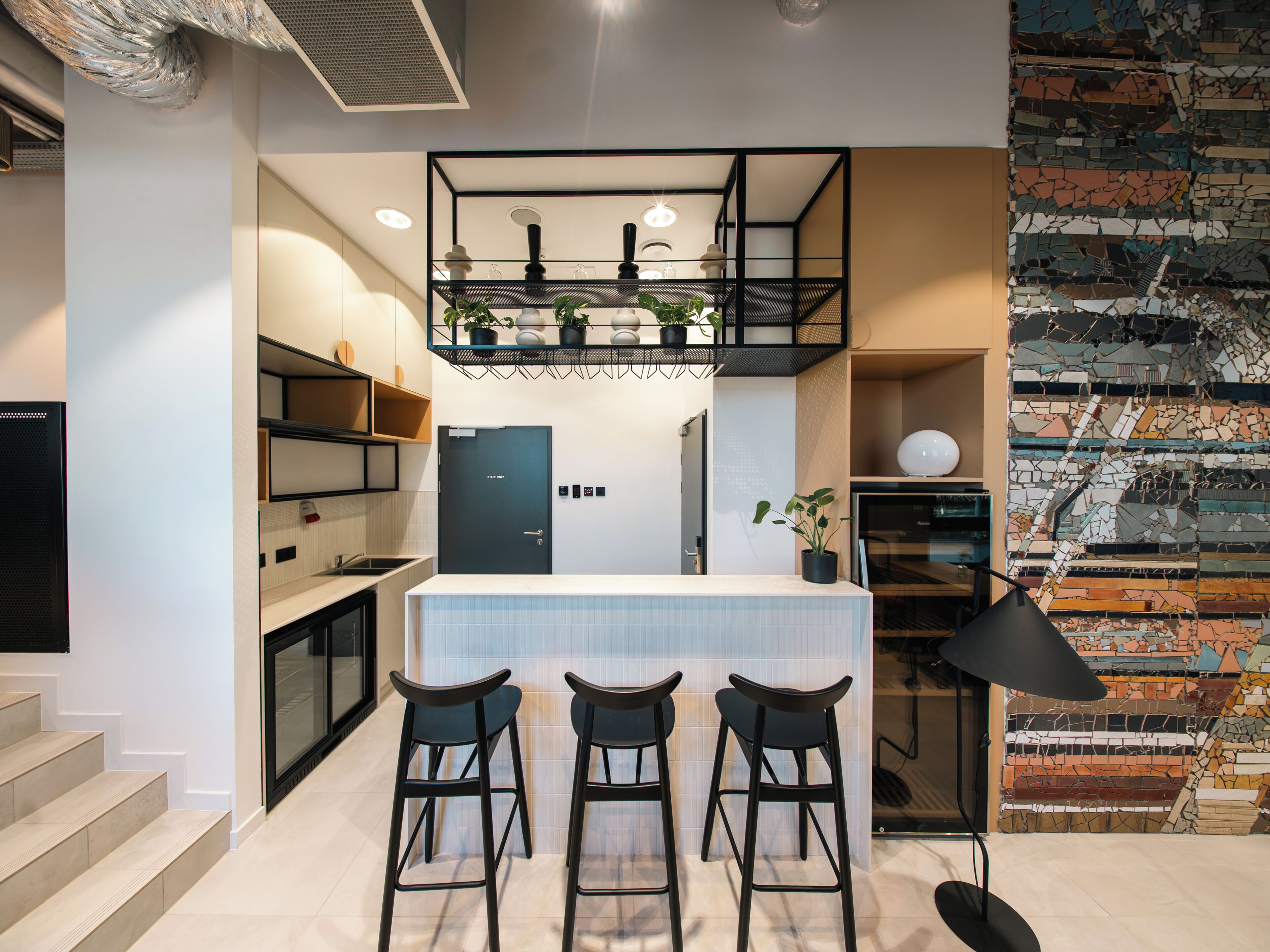 Una cocina moderna con barra, una escalera y un muro decorativo.