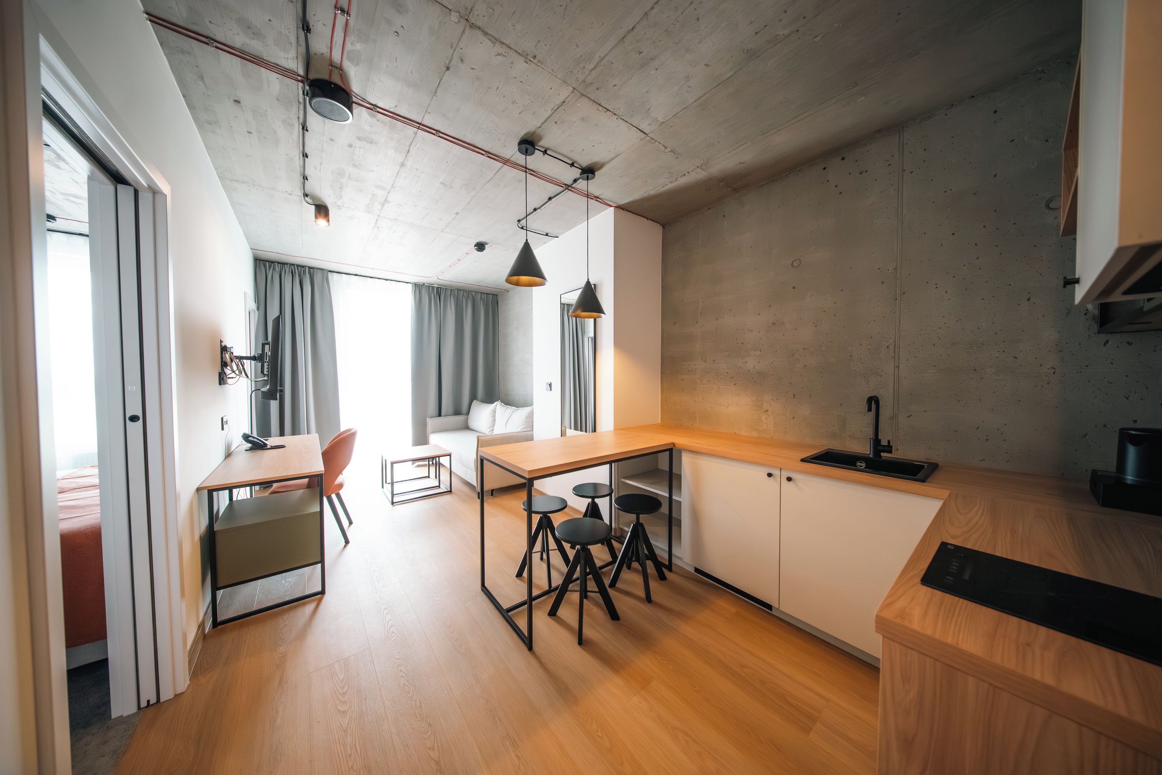 Een moderne keuken met een houten aanrecht, barkrukken en een inbouwspoelbak.