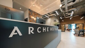 Un comptoir d’accueil sur lequel est clairement affiché le nom « ARCHE HOTEL ».