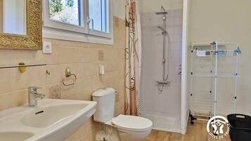 Een badkamer met een wastafel, toilet, douche en handdoekhouder.