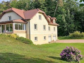 Ein zweistöckiges Haus mit geneigtem Dach, großen Fenstern und einer Veranda.
