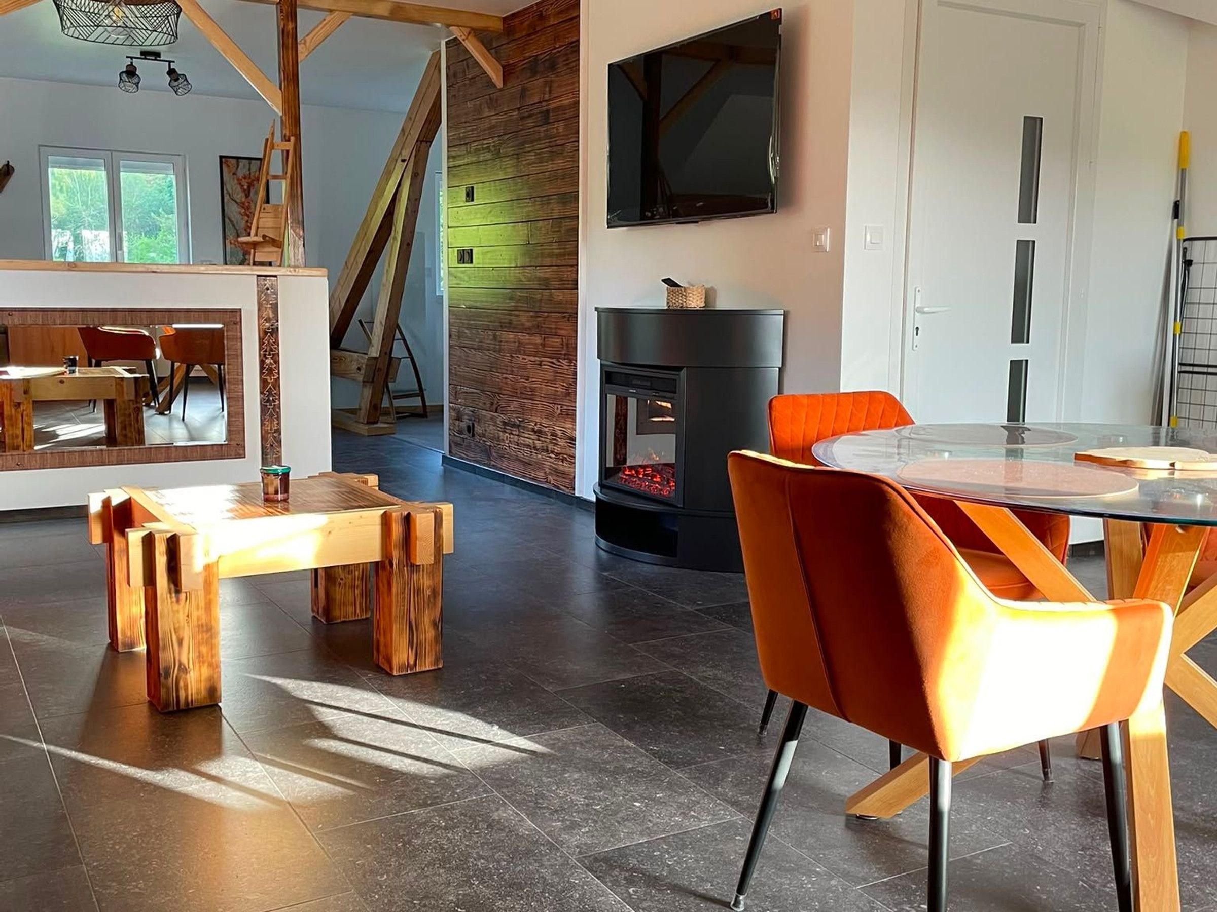 A modern interior with a fireplace, wooden furniture, and a staircase.