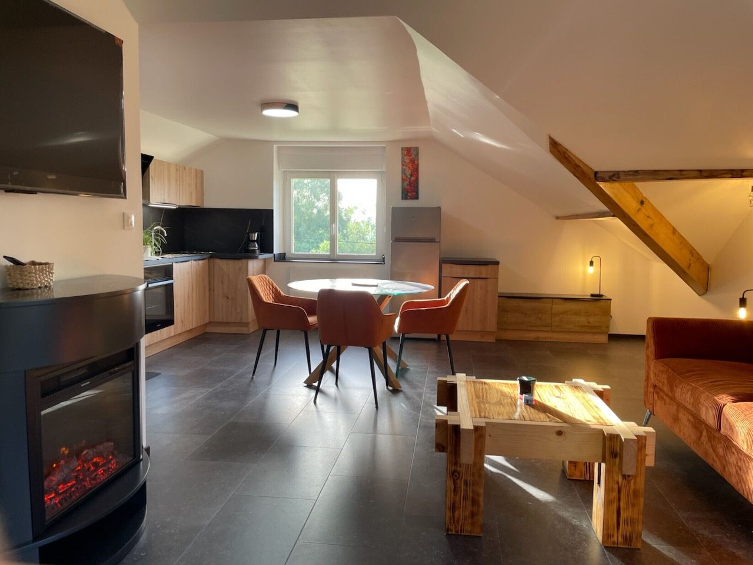 Een moderne keuken met een eethoek, een open haard en een vide met een balkenplafond.