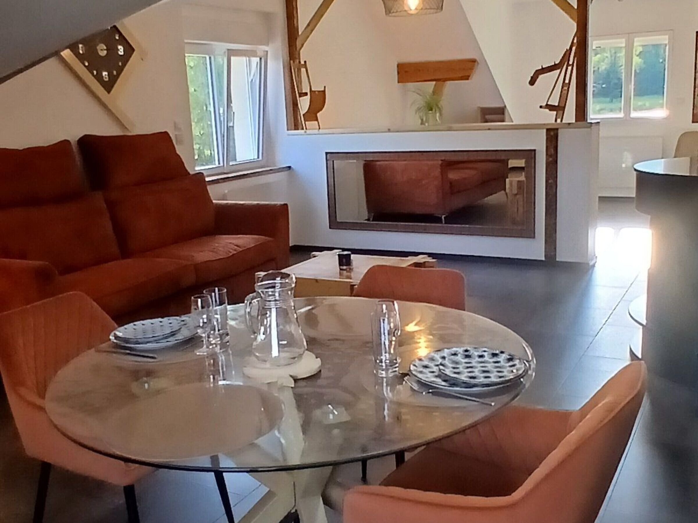 Ein modernes Wohnzimmer mit einem Glastisch, einem orangefarbenen Sofa und einem Kamin.