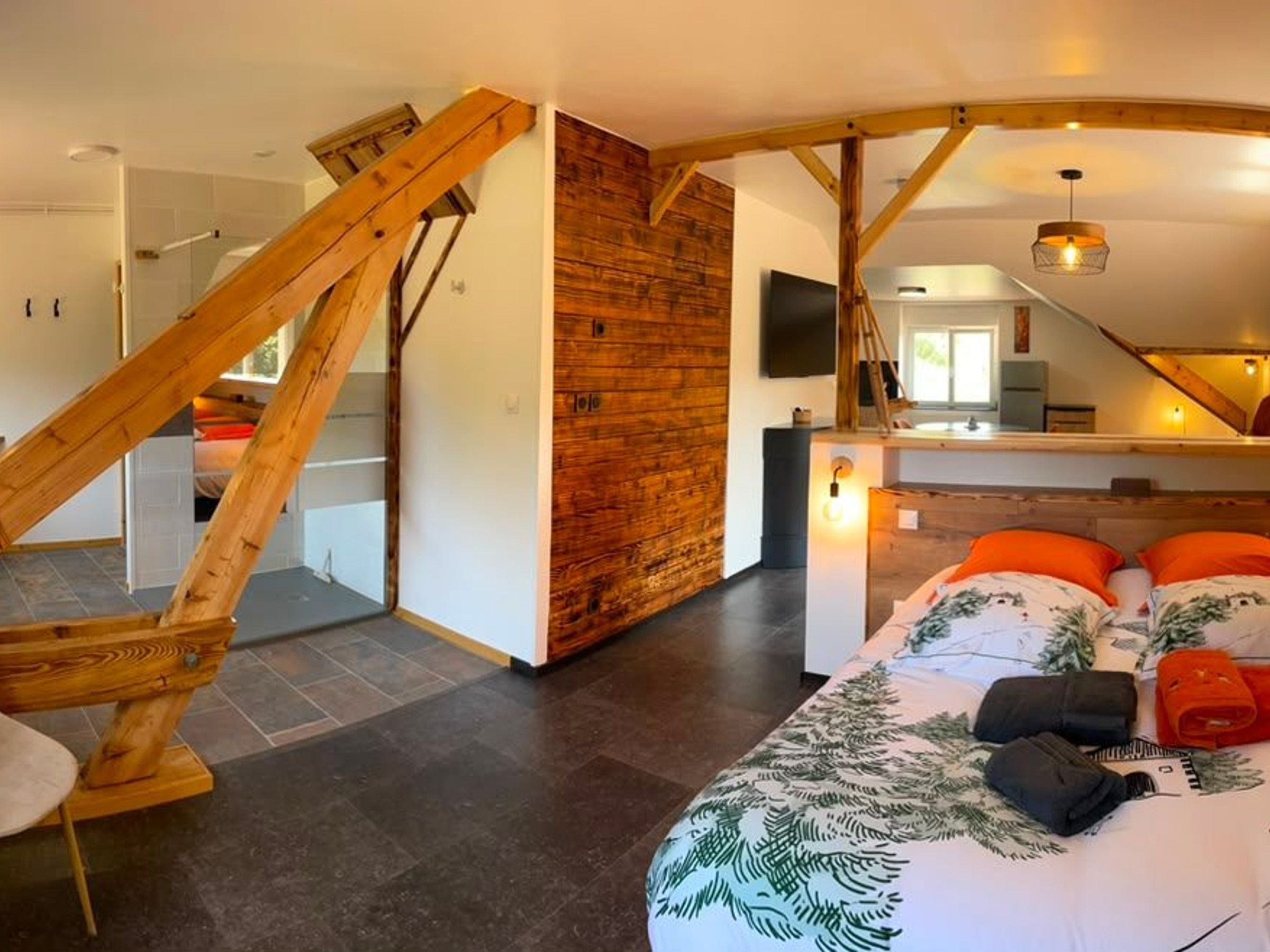 A bedroom with a bed, pillows, a wooden staircase, and a TV.