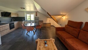 En modern lägenhet i loftstil med kök, matplats och vardagsrum.