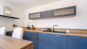Eine moderne Küche mit einer Holzauskleidung, blauen Schränken und einer Edelstahl-Dunstabzugshaube.