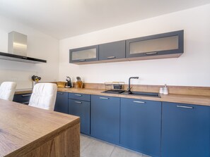 Eine moderne Küche mit einer Holzauskleidung, blauen Schränken und einer Edelstahl-Dunstabzugshaube.