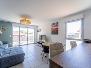 A modern living room with a sofa, a dining table, and a TV. - Modern apartment with balcony - 4 guests (Mimizan)