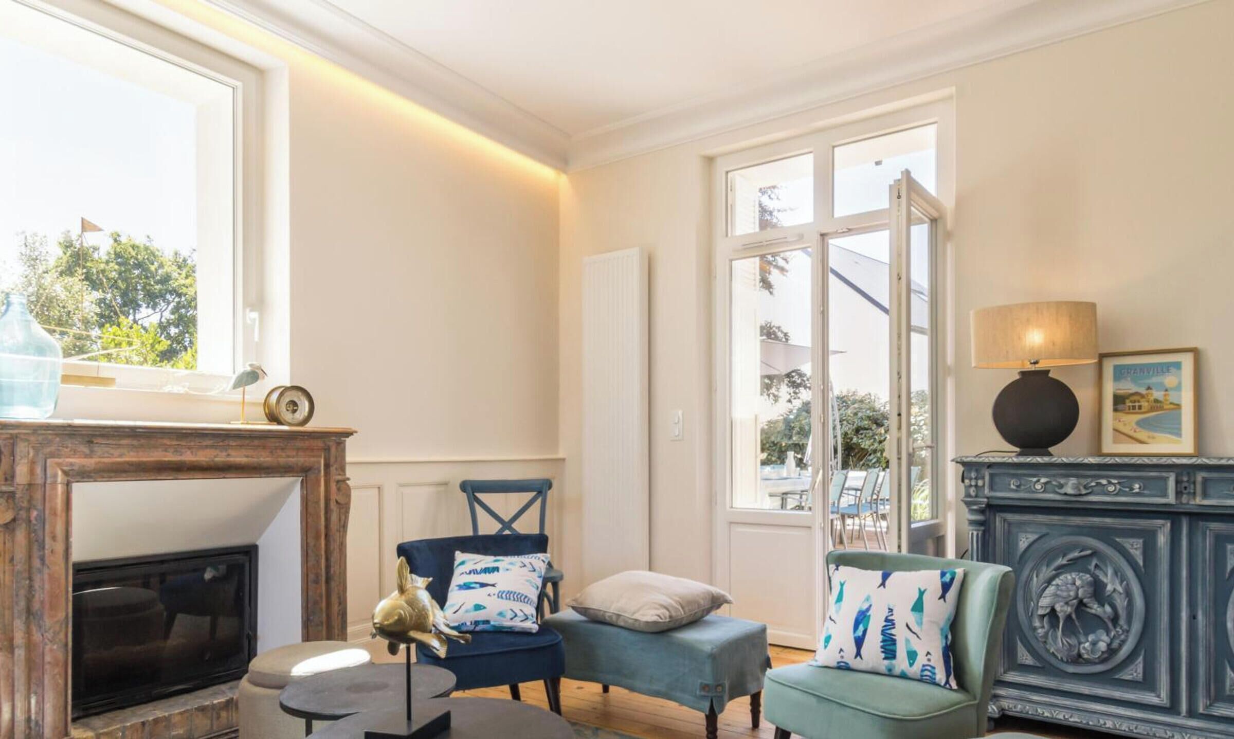 Un salon bien éclairé, doté d’une cheminée, d’un coin repas et offrant une vue sur l’extérieur.