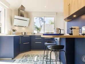 A modern kitchen with a built-in stove, a coffee maker, and bar stools. - Renovated villa with garden - 15 guests (Jullouville)