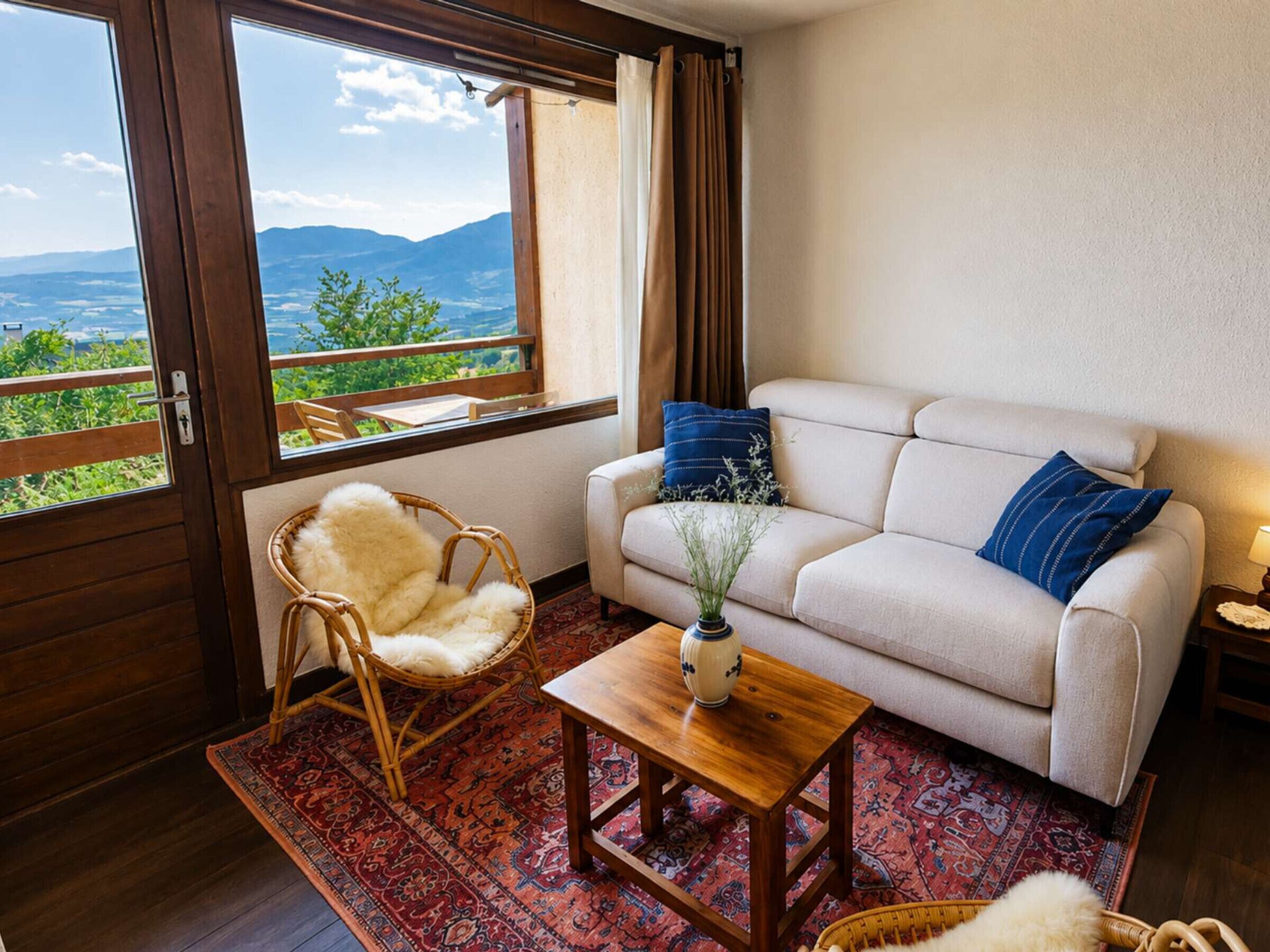 Habitació amb sofà, una cadira, taula petita i vista a l'exterior.