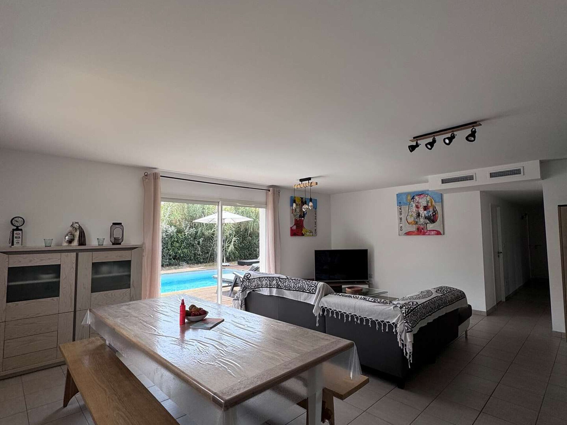 Ein Wohnzimmer mit Blick auf einen Pool, einem Essbereich und einem Fernseher.