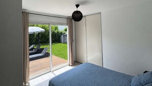 Ein Schlafzimmer mit einem Bett, einer Schiebetür zu einer Terrasse und einer Deckenleuchte.