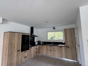 Eine moderne Küche mit Holzausstattung, einer schwarzen Dunstabzugshaube und einem Fenster, das für natürliches Licht sorgt.