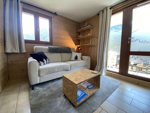 Una sala acogedora con un sofá, una mesa de centro y una estantería de madera.