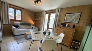 Um quarto aconchegante com uma mesa de jantar, cadeiras, um sofá e uma cozinha.