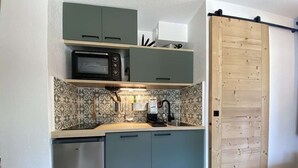 Uma cozinha compacta com micro-ondas, máquina de café e lava-louças.