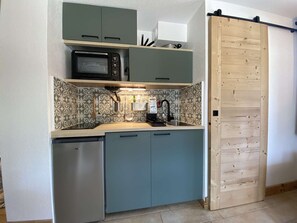 Eine kleine Küche mit Mikrowelle, Kaffeemaschine und Geschirrspüler.