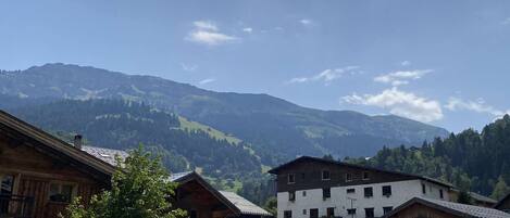 Un village de montagne avec des bâtiments traditionnels en bois, un espace de stationnement et une vue sur les collines environnantes.