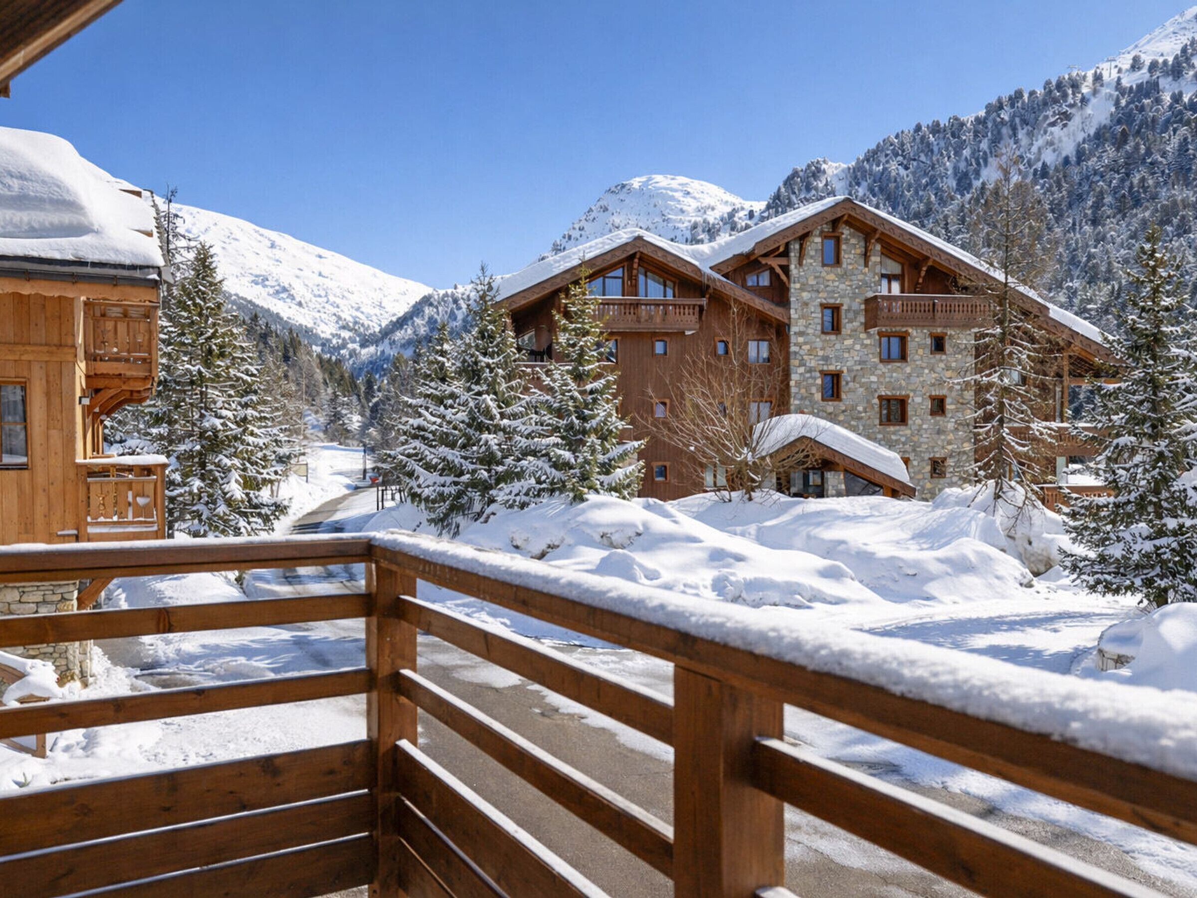 A snow-covered mountain resort with wooden buildings and a wooden deck.