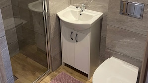 A bathroom with a glass shower enclosure, a white sink, and a toilet. - 4-person Room With Kitchenette, Sarbinowo (Mielno)